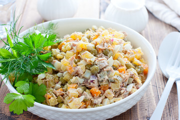 Olivier salad with boiled meat and meat on a wooden table, horizontal