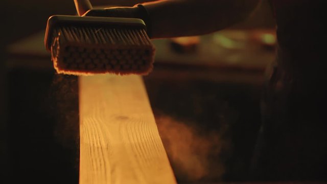 Woodworker sweeps away sawdust from treated wood. Woodworking, carpentering, craft, profession concept.
