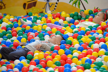 Fototapeta na wymiar the child lies in multi-colored plastic balls. playing in the playground.