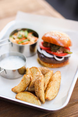 Tasty Hamburger with beef meat, potatoes, salad, tomato and onion