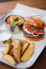 Tasty Hamburger with beef meat, potatoes, salad, tomato and onion