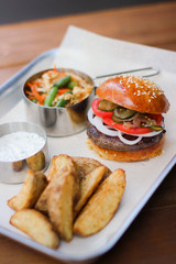 Tasty Hamburger with beef meat, potatoes, salad, tomato and onion