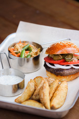 Tasty Hamburger with beef meat, potatoes, salad, tomato and onion