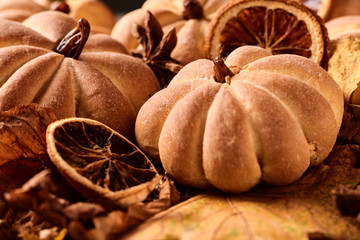 Homemade cookies in shape of pumpkin in autumn leaves. Halloween handmade cookies on a table, close up