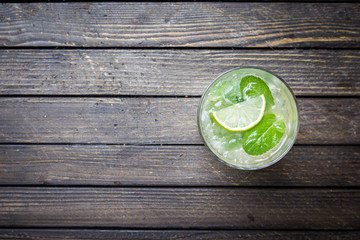 Refreshing mint cocktail mojito with rum and lime, cold drink or beverage with ice on dark wooden...
