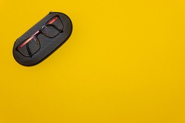 Glasses and protective case on yellow background