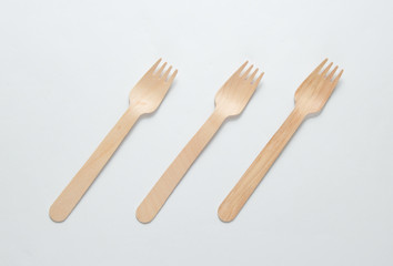 A lot of eco-friendly wooden forks on a white background. Minimalistic eco concept