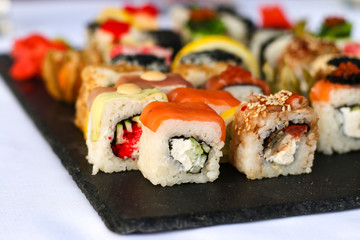 Set of sushi rolls with vasabi and ginger on a dark slate plate, Buffet table, horizontal orientation, close up