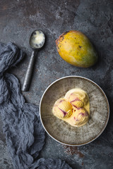 Homemade mango ice cream in a bowls with fresh fruits over dark gray background. top view with copy space