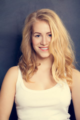 Smiling Blonde Woman on dark  background. Makeup and Curly Hairs
