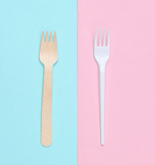 Minimalistic environmental concept. Wooden and plastic forks on a pink blue pastel background. Creative eco background