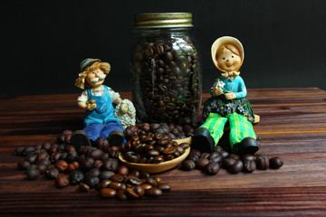 farmer dolls sit on coffee beans.dried coffee beans with roasted coffee beans .coffee beans on wood spoon on brown wood floor .