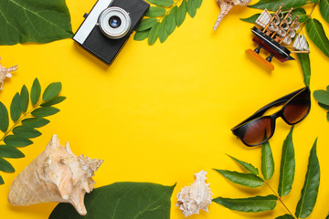 Retro style travel still life. Film camera, sunglasses, seashells, green tropical leaves. Traveler...