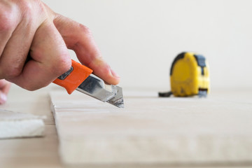 Cutting a sheet of drywall with a knife.