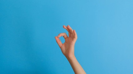 Close up of woman hand ok sign over trend blue background. Body language concept.
