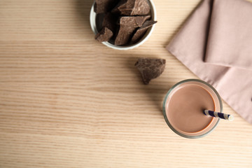 Flat lay composition with glass of tasty chocolate milk and space for text on wooden background. Dairy drink