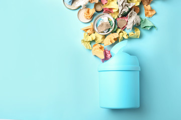 Trash bin and different garbage on color background, top view with space for text. Waste recycling...