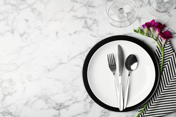 Elegant table setting with freesia on white marble background, top view. Space for text
