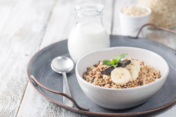 Healthy breakfast bowl. Granola with chocolate and banana on white wooden table. The concept of healthy nutrition and diet.