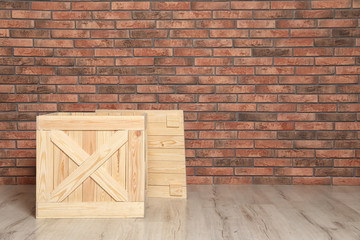 Wooden crate on floor at brick wall. Space for text