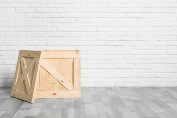Wooden crate on floor at white brick wall. Space for text