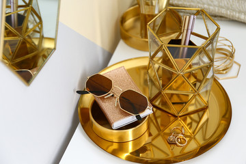 Gold tray with notebook, glasses and accessories on dressing table