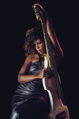 Obraz premium Sensual musician. African girl playing double bass.