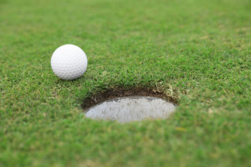 Golf ball near hole on green course