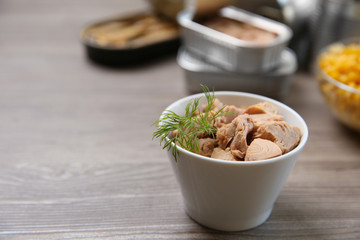 Bowl of canned tuna with dill on wooden table, space for text