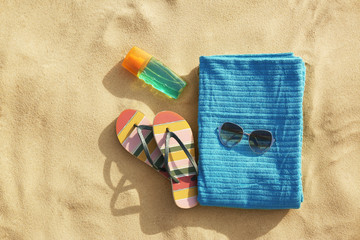 Fototapeta na wymiar Flat lay composition of beach objects and towel on sand, space for text