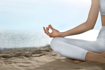 Fototapeta na wymiar Young woman practicing zen meditation on beach, closeup. Space for text