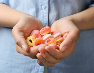 Young woman holding handful of tasty jelly candies, closeup