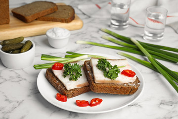 Composition with plate of pork fatback sandwiches on marble table