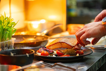 Chef finishing plate with delicious salmon, almost ready to serve at the table.