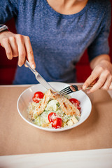 Woman's hands with Caesar salad on table in restaurant. Healthy food concept.