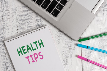 Word writing text Health Tips. Business photo showcasing advice or information given to be helpful in being healthy Top trendy metallic laptop blank spiral notepad pens lying wooden table