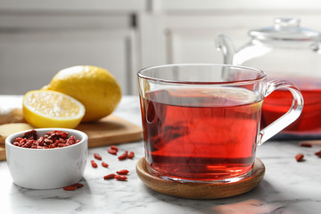 Healthy goji tea with lemon in glass cup on marble table
