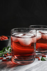 Fototapeta na wymiar Healthy goji juice with ice in glasses on table