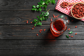 Healthy goji juice in mason jar on wooden table, flat lay. Space for text
