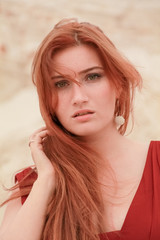 Young beautiful plus size Caucasian woman in red long chiffon dress posing in desert landscape with...