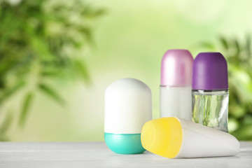 Different deodorants on white wooden table against blurred background. Space for text