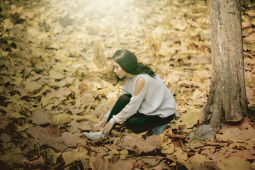 Woman binding shoelace at the autumn park