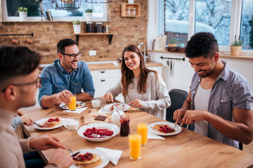 Good morning. Roommates eating breakfast talking at home in the morning.
