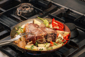 Cooking t-bone steak with vegetables.