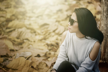 Woman sits at autumn park and wearing sunglasses