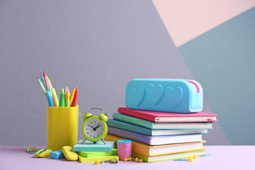 Fototapeta premium Different school stationery on table against color background