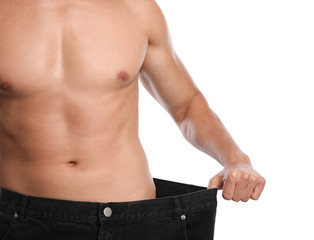 Young man with slim body in old big size jeans on white background, closeup view