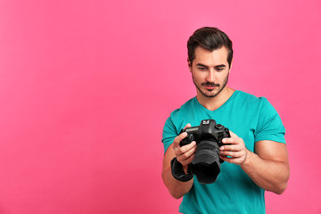Young photographer with professional camera on pink background. Space for text