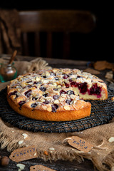 homemade tasty biscuit cake with cherries, almond flakes, powdered sugar on top