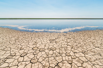 The coast of the salt lake with cracked dry ground and blue sky. Gruzskoe lake, Rostov-on-Don region, Russia